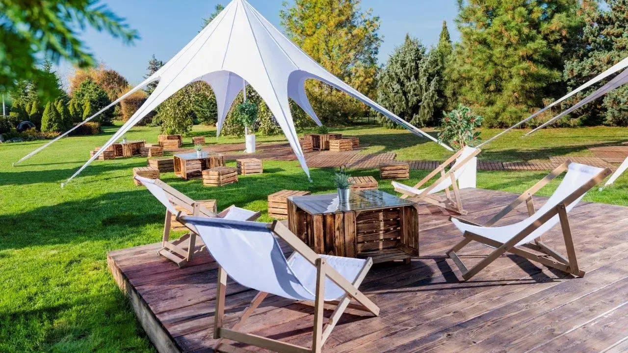 Idealna strefa chillout: leżaki, drewniane skrzynki i biały namiot tworzą relaksującą atmosferę na trawie.