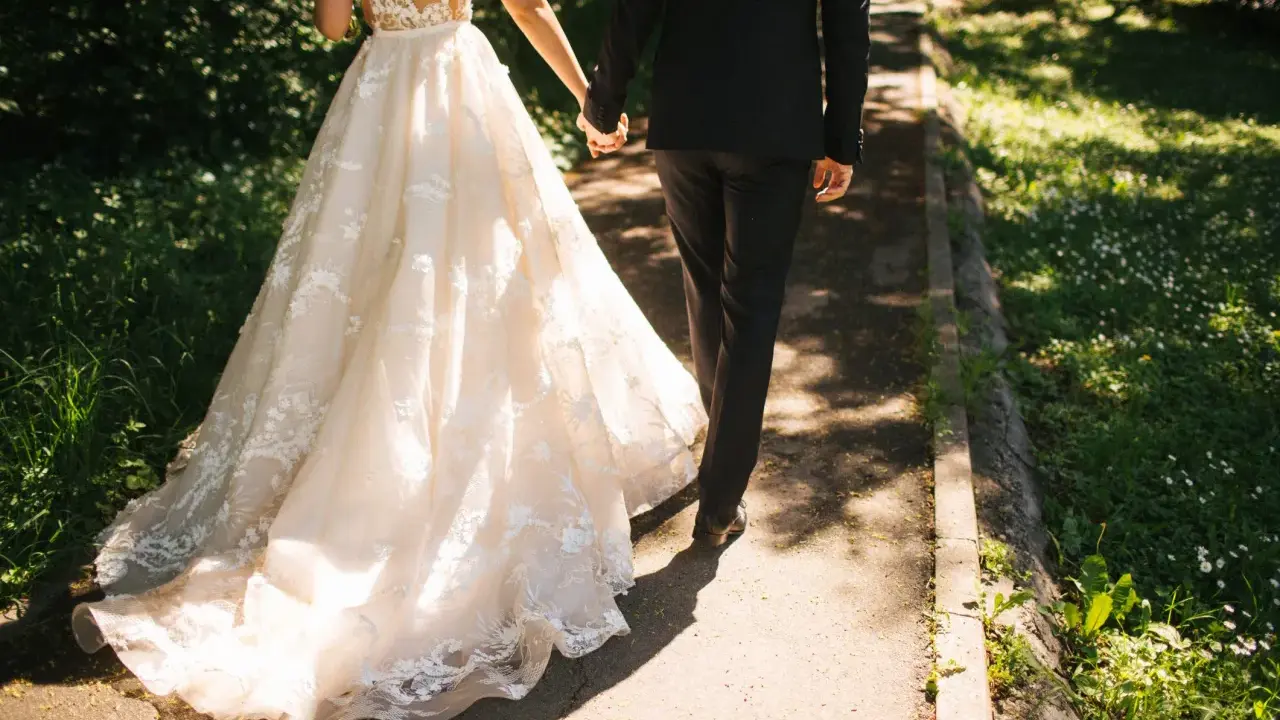 Para zjawiskowa suknia ślubna i elegancki garnitur idący ręka w rękę. Jak zareagować na zawiadomienie o ślubie?