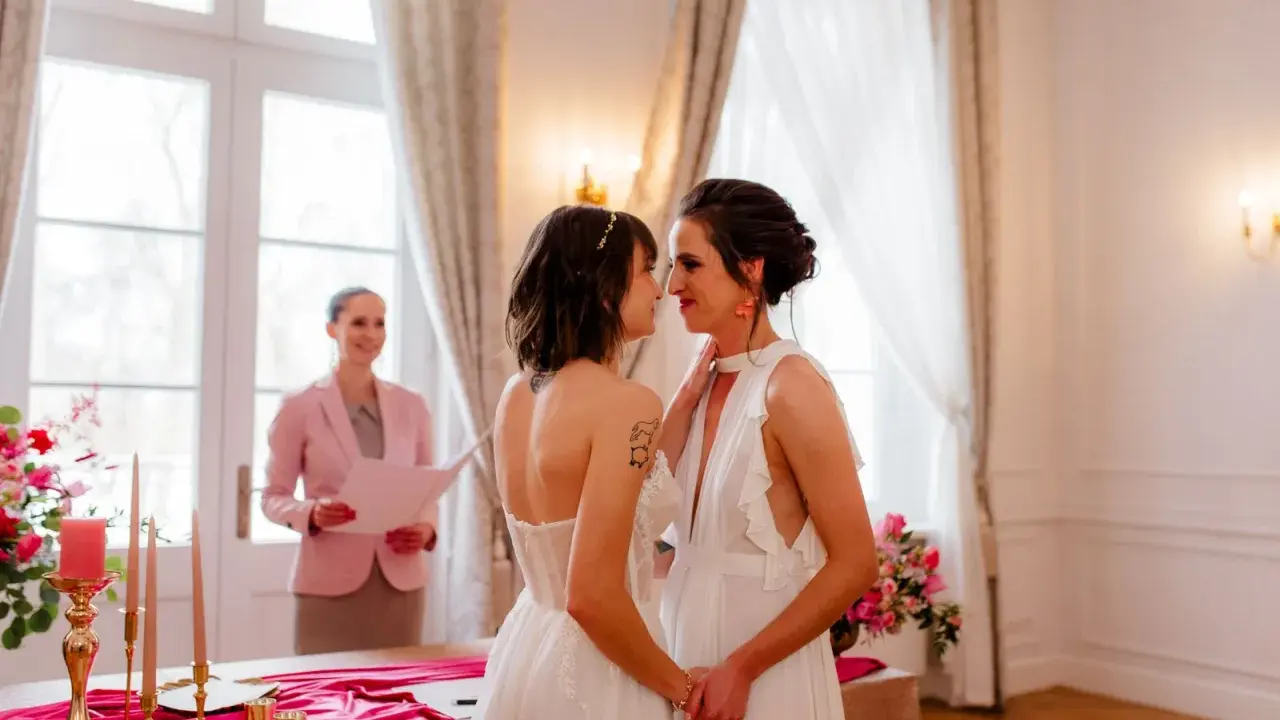 Dwie kobiety w białych sukniach ślubnych patrzą sobie w oczy podczas ceremonii. To piękny ślub homoseksualny.