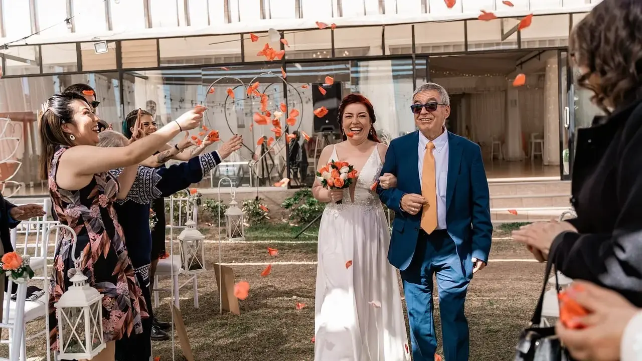 Płatki róż sypią się na parę młodą podczas uroczystości. Mimo że to slub zima, słońce świeci, a goście rzucają kwiaty.