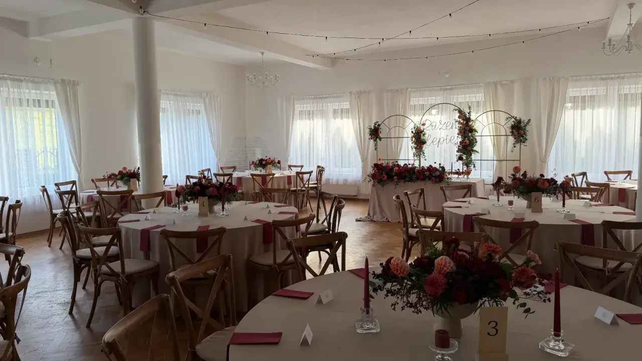 Elegancka sala weselna z okrągłymi stołami, kwiatami i świecami. Wesele co trzeba wiedzieć, by wszystko było idealne.