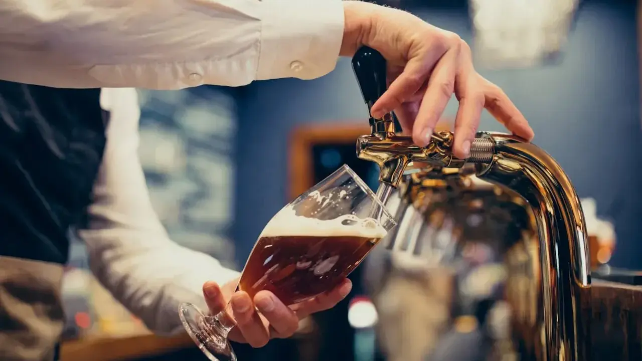 Barman nalewa piwo do kieliszka. Zastanawiasz się, ile piwa na poprawiny? To piwo wygląda pysznie!