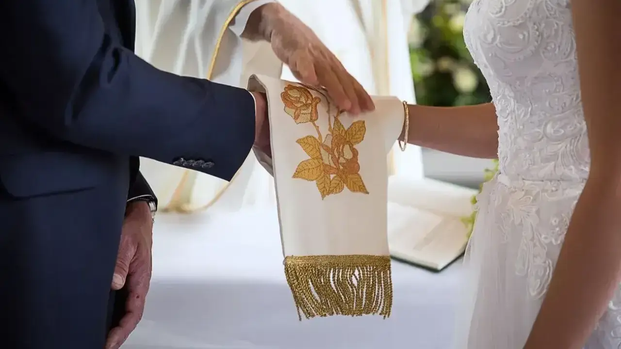 Ceremonia ślubna z kapłanem błogosławiącym ręce pary. Czy ślub kościelny ma moc prawną? To pytanie zadaje sobie wiele par.