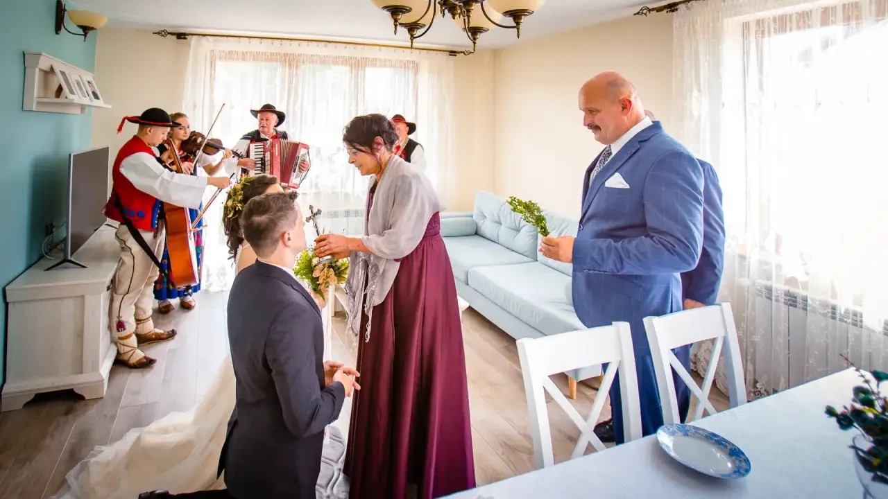 Wzruszający moment błogosławieństwa matki chrzestnej dla pary młodej, przy akompaniamencie kapeli góralskiej.
