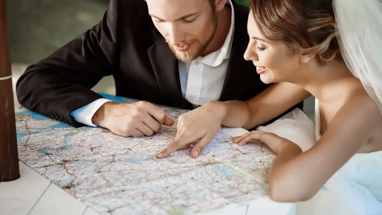 Młoda para, przygotowująca się do ślubu, planuje podróż poślubną, studiując mapę.