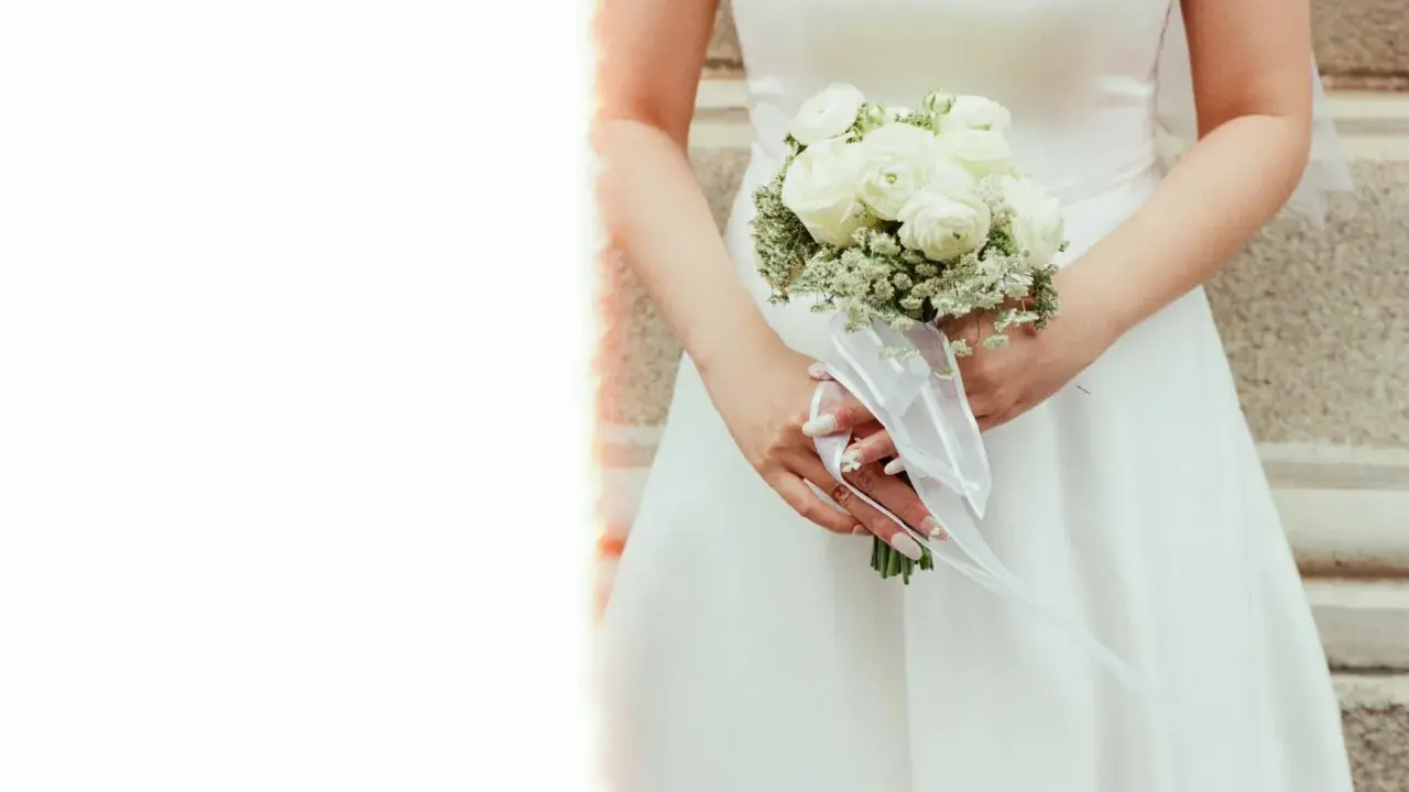 Elegancki bukiet ślubny glamour z białych róż i gipsówki, ozdobiony białą wstążką.