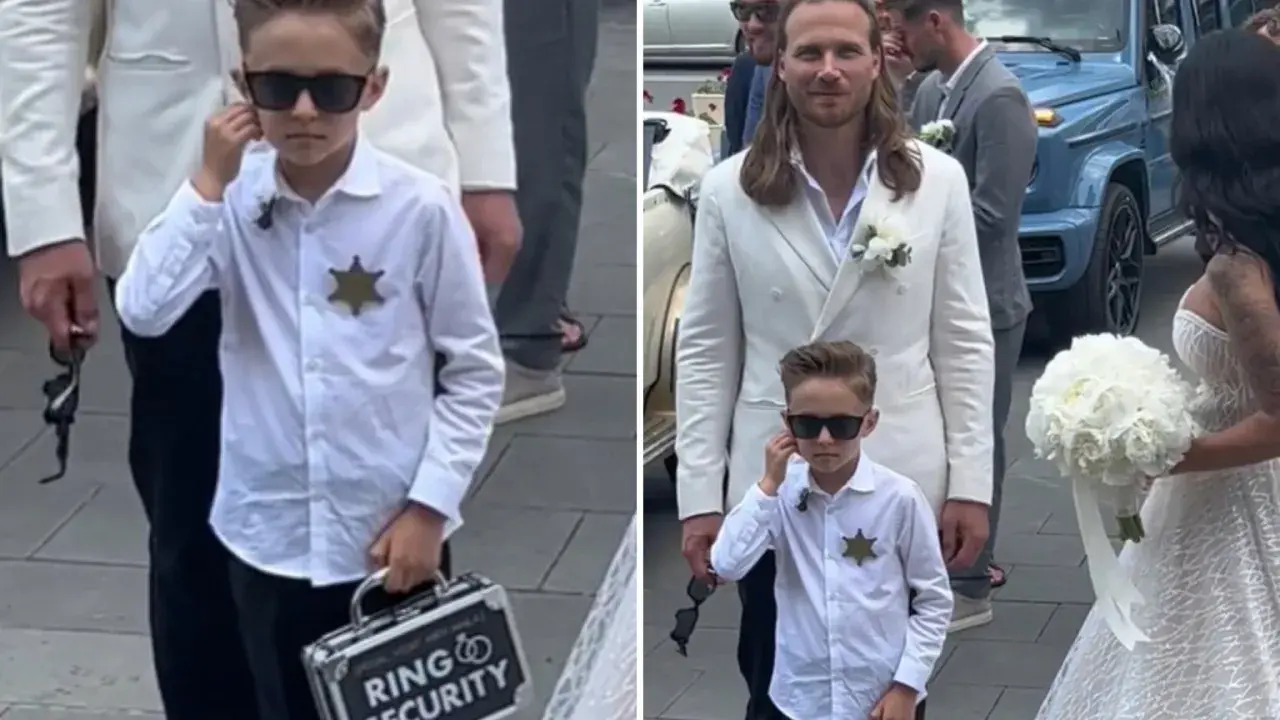 Chłopiec w okularach przeciwsłonecznych, z odznaką i walizką "Ring Security", niesie obrączki do ślubu.