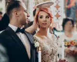 Para młoda podczas ceremonii ślubnej. Panna młoda w koronkowej sukni i pan młody w garniturze, trzymają świece.
