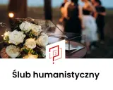 Białe róże z lampkami, szklana szkatułka i rozmyte sylwetki ludzi w tle. To piękny ślub humanistyczny.