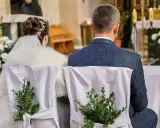 Para młoda siedzi w kościele. Krzesła ozdobione zielonymi gałązkami. Kto nie może być świadkiem na ślubie kościelnym?