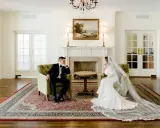 Para młoda siedzi w fotelach, zastanawiając się, ile trwa ślub cywilny. Eleganckie wnętrze z kominkiem i obrazem.