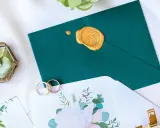 Elegancka koperta na wesele z pieczęcią, obrączki i ozdobne pudełeczko z suszonymi kwiatami.