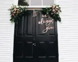 Eleganckie dekoracje wejścia do domu pana młodego: bukiety róż i zieleni oraz napis "It was always you".