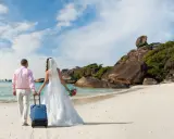 Para podróż poślubna we wrześniu: para młoda na tropikalnej plaży z walizką, gotowa na przygodę.