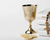 Złoty kielich, hostie, różaniec i Biblia. Symbolika sakramentów, od chrztu do ślubu, przygotowująca do życia w wierze.
