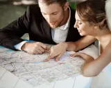 Młoda para, przygotowująca się do ślubu, planuje podróż poślubną, studiując mapę.