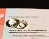 Złote obrączki na odpisie skróconym aktu małżeństwa po ślubie cywilnym. Dokument z Urzędu Stanu Cywilnego w Katowicach.