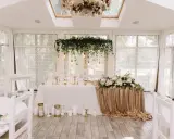 Elegancka sala weselna z białymi krzesłami i stołem pary młodej ozdobionym złotymi cekinami i kwiatami. Wspaniałe kolory na wesele.