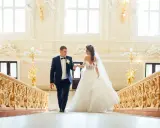 Para Młoda idzie po schodach ozdobionych bogatą dekoracją schodów na wesele.