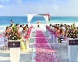 Plażowa ceremonia ślubna z różowymi płatkami kwiatów i błękitnym oceanem w tle. Idealne, nietypowe miejsce na wesele marzeń.