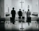 Para młoda i ksiądz podczas ślubu w kościele. W tle krzyż. W odbiciu na podłodze widać, jakby pieniądze w bucie ślubnym.