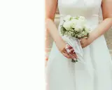 Elegancki bukiet ślubny glamour z białych róż i gipsówki, ozdobiony białą wstążką.
