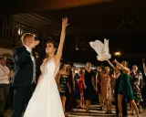 Panna młoda rzuca welonem, tradycyjny moment oczepin. Goście weselni obserwują z ekscytacją.
