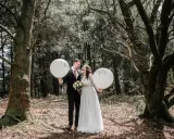 Para młoda w lesie, trzymająca balony z napisami "Mr" i "Mrs". Piękne sesja ślubna inspiracje.