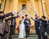 Para młoda przechodzi pod łukiem z szabel, tworząc tradycyjne wejście do kościoła ślub.