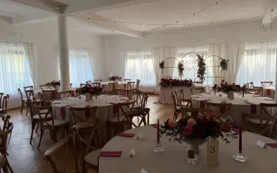Elegancka sala weselna z okrągłymi stołami, kwiatami i świecami. Wesele co trzeba wiedzieć, by wszystko było idealne.