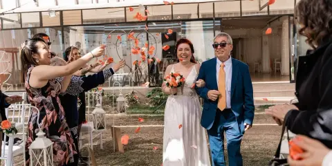 Płatki róż sypią się na parę młodą podczas uroczystości. Mimo że to slub zima, słońce świeci, a goście rzucają kwiaty.