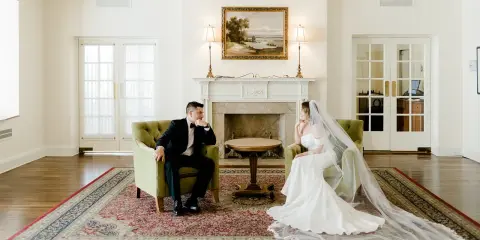 Para młoda siedzi w fotelach, zastanawiając się, ile trwa ślub cywilny. Eleganckie wnętrze z kominkiem i obrazem.