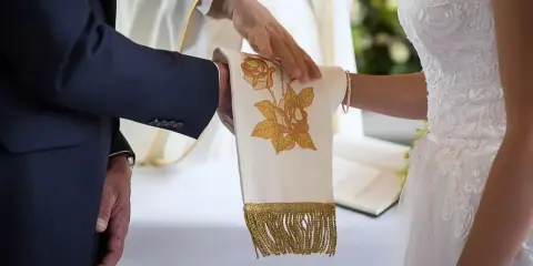 Ceremonia ślubna z kapłanem błogosławiącym ręce pary. Czy ślub kościelny ma moc prawną? To pytanie zadaje sobie wiele par.