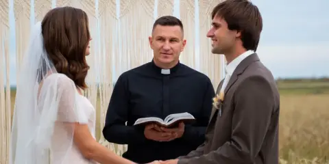 Para młoda trzyma się za ręce, ksiądz błogosławi ich przed ślubem.