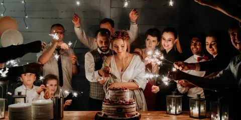 Para młoda kroi tort wśród rodziny i przyjaciół z zimnymi ogniami. Wspaniała alternatywa dla pierwszego tańca!