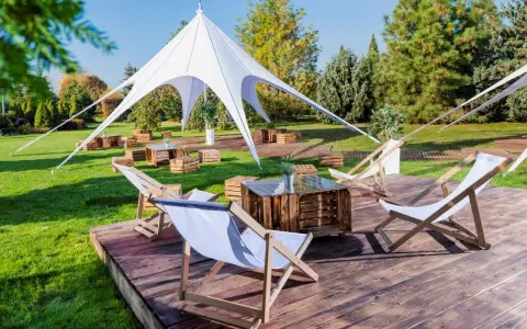 Idealna strefa chillout: leżaki, drewniane skrzynki i biały namiot tworzą relaksującą atmosferę na trawie.