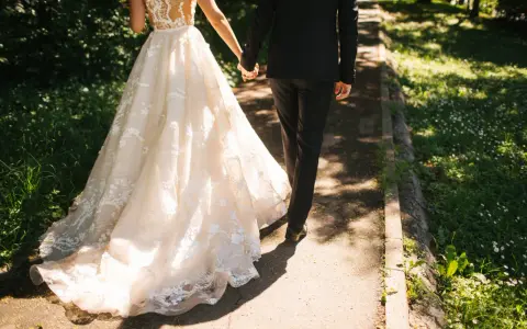 Para zjawiskowa suknia ślubna i elegancki garnitur idący ręka w rękę. Jak zareagować na zawiadomienie o ślubie?