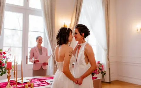 Dwie kobiety w białych sukniach ślubnych patrzą sobie w oczy podczas ceremonii. To piękny ślub homoseksualny.