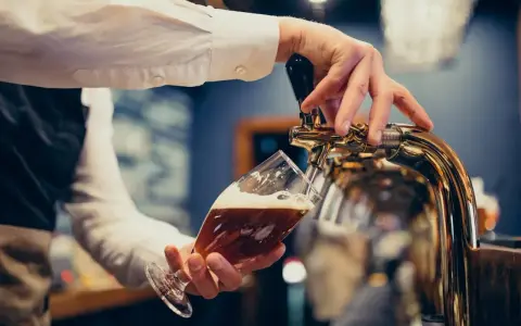 Barman nalewa piwo do kieliszka. Zastanawiasz się, ile piwa na poprawiny? To piwo wygląda pysznie!
