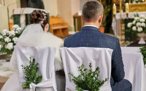 Para młoda siedzi w kościele. Krzesła ozdobione zielonymi gałązkami. Kto nie może być świadkiem na ślubie kościelnym?