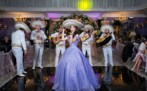 Dziewczyna w fioletowej sukni i mariachi śpiewają, tworząc atmosferę pełną radości i być może sprośnych przyśpiewek.