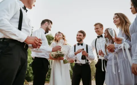 Para młoda świętuje z przyjaciółmi. Czy świadek może być po ślubie? Oczywiście, że tak! Wszyscy są uśmiechnięci i trzymają kieliszki.