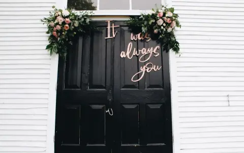 Eleganckie dekoracje wejścia do domu pana młodego: bukiety róż i zieleni oraz napis "It was always you".