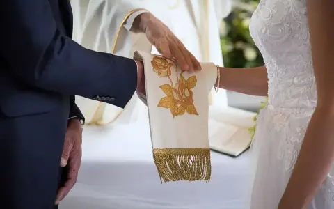 Ceremonia ślubna z kapłanem błogosławiącym ręce pary. Czy ślub kościelny ma moc prawną? To pytanie zadaje sobie wiele par.