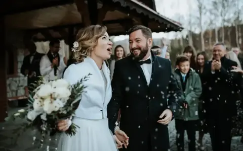Para młoda wychodzi z kościoła, obsypana konfetti. Mimo że to najgorszy miesiąc na ślub, ich uśmiechy rozświetlają zimny dzień.