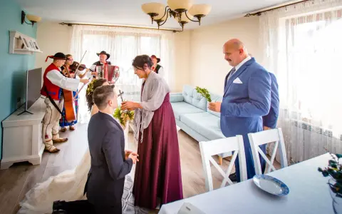 Wzruszający moment błogosławieństwa matki chrzestnej dla pary młodej, przy akompaniamencie kapeli góralskiej.