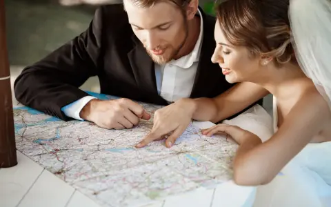 Młoda para, przygotowująca się do ślubu, planuje podróż poślubną, studiując mapę.