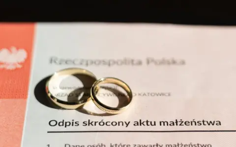 Złote obrączki na odpisie skróconym aktu małżeństwa po ślubie cywilnym. Dokument z Urzędu Stanu Cywilnego w Katowicach.