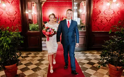 Para idzie po czerwonym dywanie, ona w białej sukni z bukietem, on w granatowym garniturze. To ich ślub rzymski.