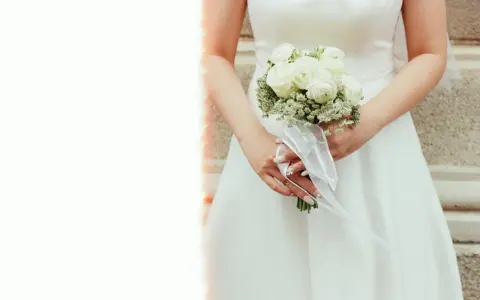 Elegancki bukiet ślubny glamour z białych róż i gipsówki, ozdobiony białą wstążką.